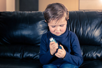 little boy in sofa and with asthma inhaler