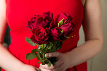 Beautiful woman holding red rose bouquet, romantic Valentines day surprise.