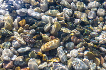 sea pebble beach with multicoloured stones, waves with foam