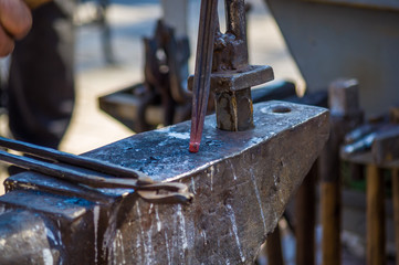blacksmith performs the forging of hot glowing horseshoe on the anvil