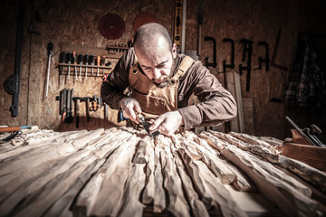 Caucasian carpenter intent on carving wood in his workshop. traditional and manual work concept.