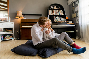 Obraz premium Loving young couple sitting on the floor in the room