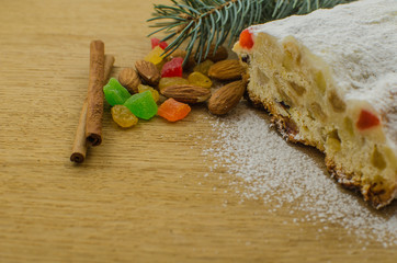 Christmas stollen on darkfestive background with fir twigs, lights and and berries. Close-up on this traditional German dessert
