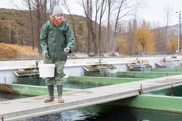 Female owner on sturgeon farm feeding fish