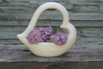 Букет  сирени  в белой вазе на  сером фоне крупным планом 