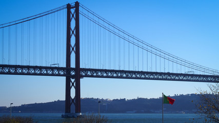 Portuguese flag on the  25 de Abril Bridge background, Lisbon, Portugal