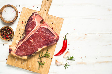 T-bone beef steak on white with spices. 