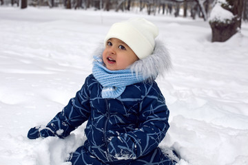 Obraz premium baby boy in the winter in blue overalls on the street