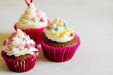 celebratory cupcake for Valentines day and happy birthday on wooden white background with hearts. Give love on a holiday