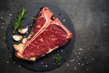 T-bone beef steak on black with spices. 
