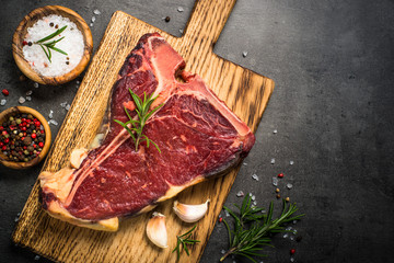 T-bone beef steak on black with spices. 