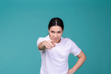 Fototapeta premium Mad angry young brunette woman staring at someone and pointing him with finger. blaming all her failures on you