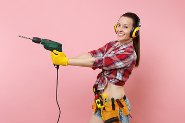 Energy sexy handyman woman in gloves, noise insulated headphones, kit tools belt full of...