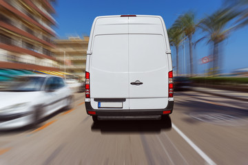 Transporter oder Lieferwagen fährt auf einer Straße bei blauem Himmel und liefert Pakete aus.