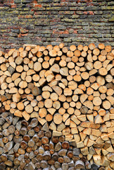 Stack of firewood on a old weathered brick wall background