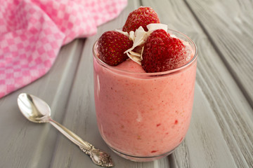 Yogurt with frozen strawberry on the grey wooden background