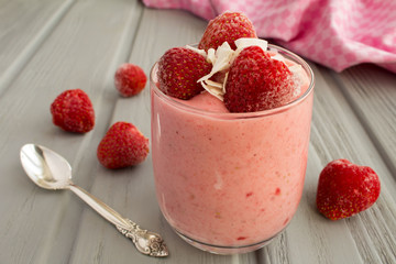 Yogurt with frozen strawberry on the grey wooden background
