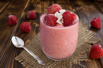 Yogurt with frozen strawberry on the rustic wooden background