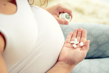 Closeup of pregnant woman's hand with pills.