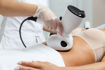Cosmetologist making radio waves lifting therapy procedure for abdomen