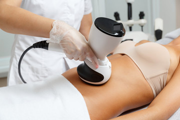 Cosmetologist making radio waves lifting therapy procedure for abdomen