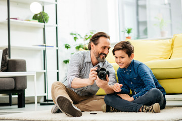 Excited parent teaching his son how to use modern camera
