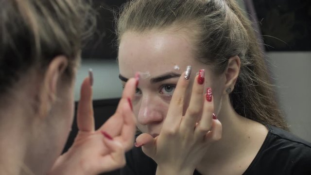 Teen girl applying anti acne cream on problem face. Treat pimples. Skin care