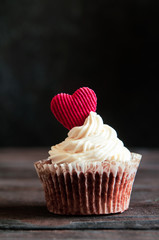 celebratory cupcake for Valentines day and happy birthday on wooden black background with hearts. Give love on a holiday