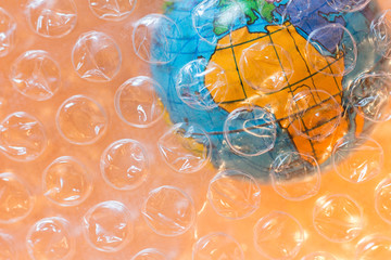 Plastic and pollution in Africa concept. Bubble wrap on earth globe on orange/yellow background