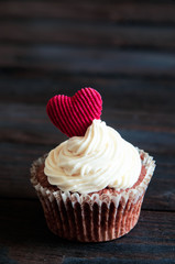 celebratory cupcake for Valentines day and happy birthday on wooden black background with hearts. Give love on a holiday