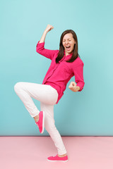 Full length portrait of smiling young pretty woman in rose shirt blouse, white pants posing isolated on bright pink blue pastel wall background studio. Fashion lifestyle concept. Mock up copy space.