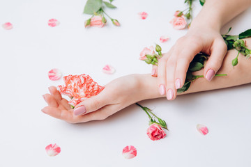 Fototapeta na wymiar Creative photo of fashion female hands with clean skin and pink manicure hold flowers in hand on white background.