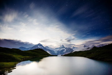 High mountain peaks glowing in the moonlight. Location place Bachalpsee in Swiss alps, Grindelwald valley.