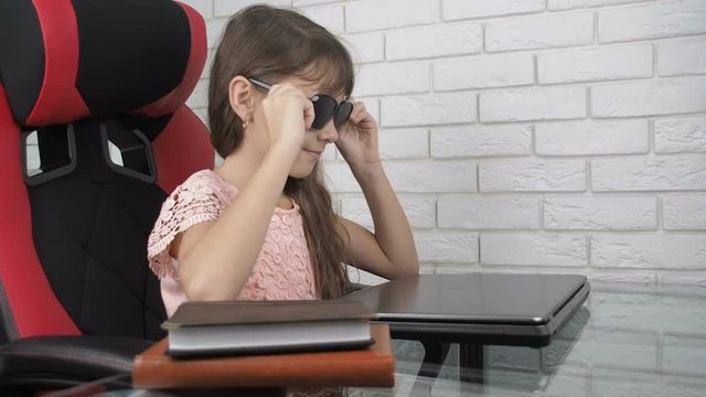 Girl sitting in front of laptop with pinhole glasses. Girl behind a laptop with obscura glasses.