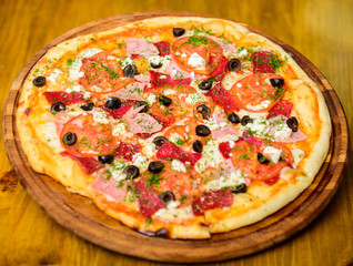 Delicious hot pizza on wooden board plate. Food delivery service. Pizza with pepperoni, tomatoes and black olives. Take away food concept. Pizzeria restaurant. Pizza with chopped dill. Italian pizza