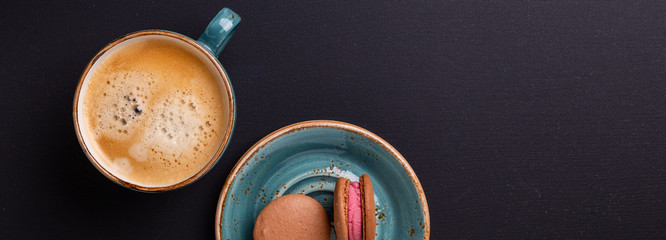 Blue cup of coffee and macaroons on the dark wooden table. Coffe break. Top view. Flat lay Web banner