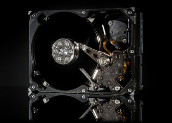Disassembled and opened hard disk drive, inside view with reflections, isolated on black