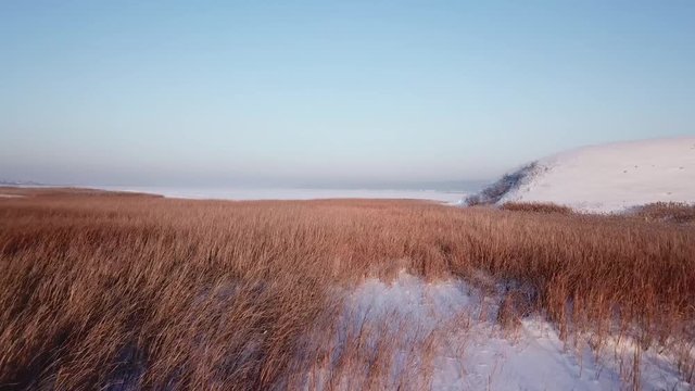 4k aerial photography. Winter landscape with a view of the frozen river. Shrubs. Warm sunset light.