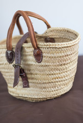Fototapeta na wymiar A light hand crafted hippy wicker weaved and woven carrying bag. Eco friendly made with sustainable reusable recycled products. Leather handles.