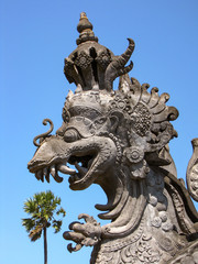 Fototapeta na wymiar Illusion of a giant hindu dragon eating a palm tree, street ornament in Bali, Indonesia