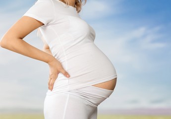 Pregnant young woman in white t shirt on bright background