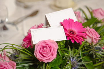 An empty blank paper table card name plate sign on a wedding table, with beautiful pink flowers shot with a shallow depth of field. perfect for placing names in composite designs.