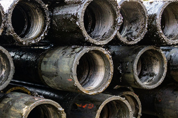 Oil Drill pipe. Rusty drill pipes were drilled in the well section. Downhole drilling rig. Laying the pipe on the deck. View of the shell of drill pipes laid in courtyard of the oil and gas warehouse.