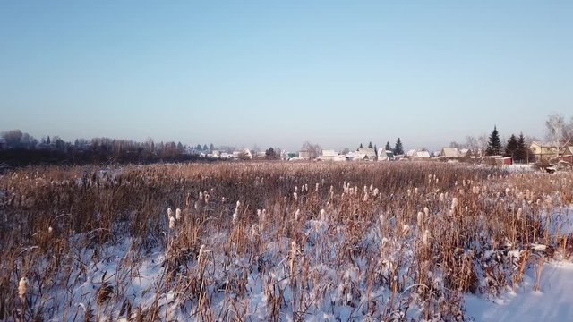 4k aerial photography. Winter landscape with a view of the frozen river. Shrubs. Warm sunset light.