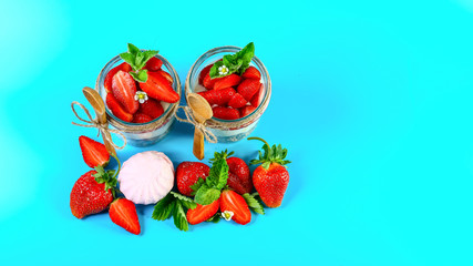 Obraz na płótnie Canvas Strawberry with whipped cream in a glass. Gourmet dessert with fresh summer berries and lush cream Isolated on a blue background. Copy space