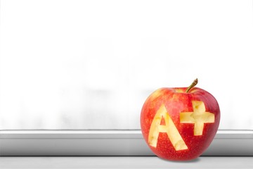 Photo of red apple with A+ on the school desk
