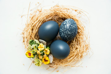 colored Easter eggs in nest on wooden background, selective focus image. Happy Easter card 