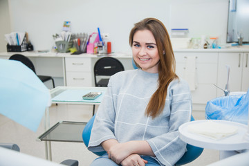 Obraz na płótnie Canvas Female patient at dentist cabinet scared of tooth cure. Young woman holding cheek sitting at stomatologist armchair.