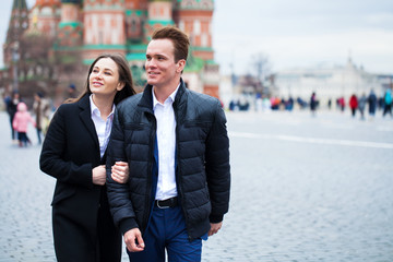 Portrait of a young couple in coat walking on a red square in the center of Moscow