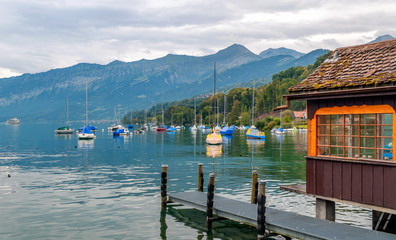 Naklejka premium Lake in Switzerland with boats on a cloudy day with mountains in the background